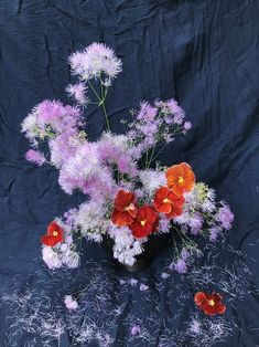 a black vase filled with lots of pink and red flowers