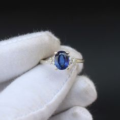 a blue sapphire and diamond ring sitting on top of a white glove