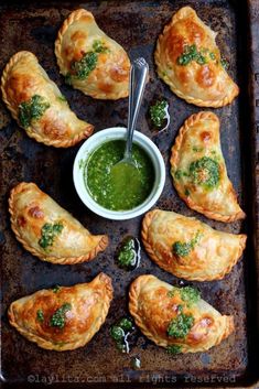 several pastries on a baking sheet with green sauce