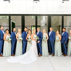 a large group of people standing together in front of a building with one woman wearing a wedding dress