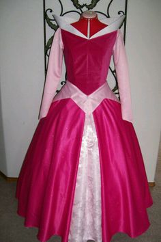 a pink and white dress on display in front of a wall with an iron frame