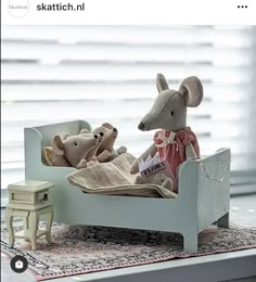 there is a toy bed with two stuffed animals in it and a small table next to it