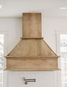 a large wooden stove top mounted to the side of a white wall in a kitchen