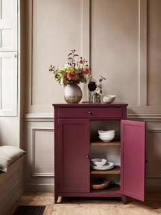 a vase with flowers sitting on top of a cabinet