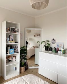 a bedroom with white furniture and plants in the corner