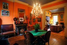 the dining room is decorated in orange and green with chandeliers hanging from the ceiling