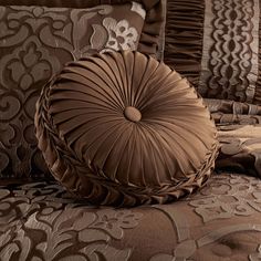 a brown pillow sitting on top of a bed next to pillows and blankets with ruffled edges