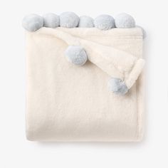 a white blanket with pom poms on it and two blue balls hanging from the top