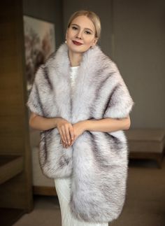 a woman in a white dress is wearing a fur shawl and posing for the camera