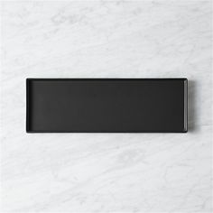 a black rectangular tray sitting on top of a white marble countertop next to a wall