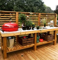 a wooden deck with potted plants and a grill on the table next to it