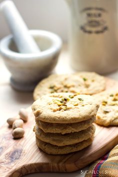 a stack of cookies sitting on top of a wooden cutting board next to some nuts