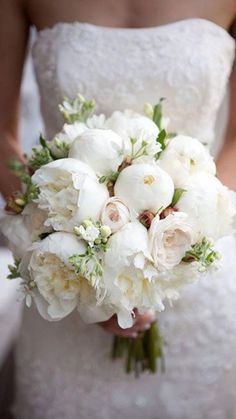 a bride holding a bouquet of white flowers