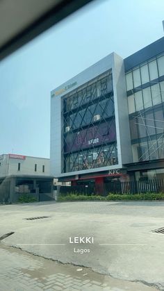 a large building sitting next to a parking lot in front of a tall glass building