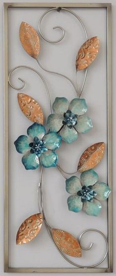 a metal wall hanging with flowers and leaves on it's side in a silver frame