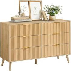 an image of a wooden dresser with plants and pictures on the top, next to a mirror