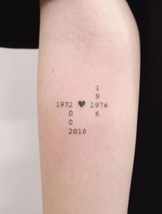 a woman's arm with numbers and hearts tattooed on the back of her left arm