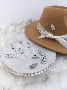 two hats, one with feathers and the other with pins on it sitting on a fur rug