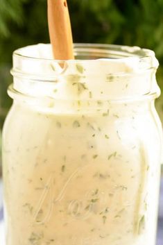 a jar filled with white liquid sitting on top of a table next to a wooden spoon