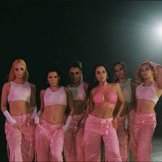 a group of women standing next to each other in pink pants and bras with their hands on their hips