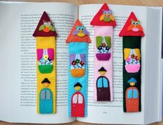 an open book with three felt houses on it's pages and one has two owls in the windows