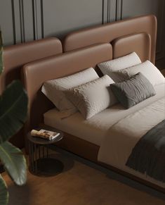 a bed with white and grey pillows on top of it next to a wooden headboard