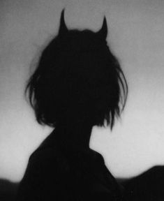 a black and white photo of a person with horns on their head looking at something