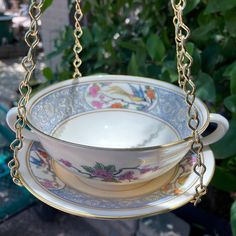 a teacup and saucer hanging from a chain