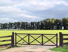 an open gate in the middle of a grassy field