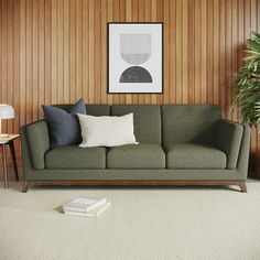 a living room with wood paneling and a green couch in front of a white rug