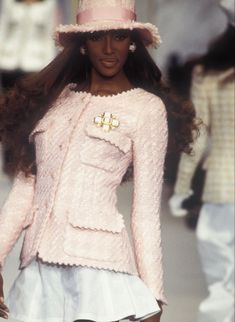 a model walks down the runway wearing a pink hat