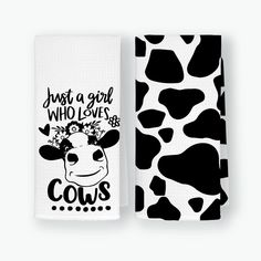 two hand towels with black and white cow print on them, one has the words just a girl who loves cows