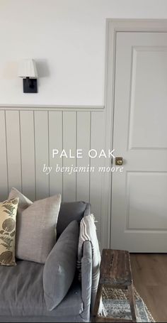 a grey couch sitting in front of a white door with the words pale oak on it