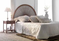 a bed with white linens and pillows in a room next to a lamp on a table