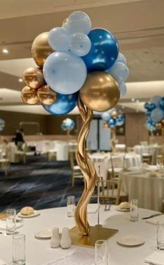 a table topped with lots of blue and gold balloons in the shape of a tree