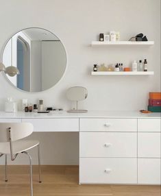 a white desk with a mirror and some shelves on the wall next to each other