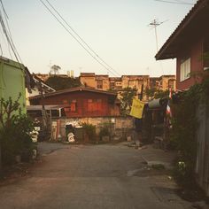 an alley way with houses and power lines in the backgrouds on either side