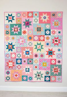 a pink and blue quilt hanging on the wall