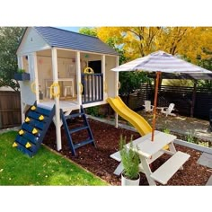 there is a small play house with a slide in the back yard, and an umbrella over it