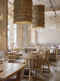 an empty restaurant with wooden tables and chairs, hanging chandeliers above the tables