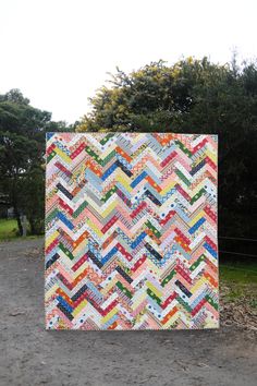 a colorful quilt on the ground next to some trees