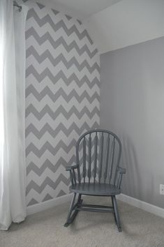 a chair sitting in front of a wall with chevron wall stencil on it