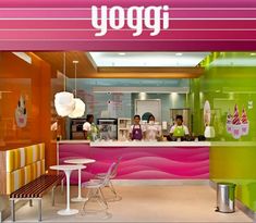 the interior of a yogurt shop with colorful walls and tables in front of it