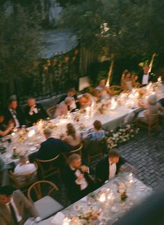 a group of people sitting at tables with candles on them