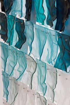 several pieces of glass hanging on the wall in front of a white wall with black and blue wavy lines