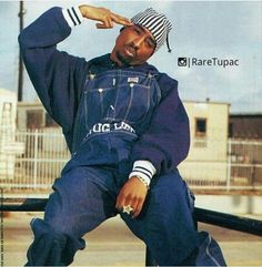 a man sitting on top of a skateboard wearing a blue jean jacket and striped hat