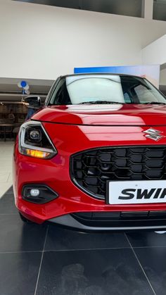 the front end of a red car in a showroom