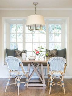 a dining room table with two chairs and a lamp hanging from the ceiling above it