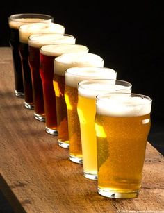 a row of glasses filled with different types of beer