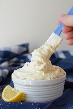 a person is dipping something into a small white bowl with lemon wedges on the side